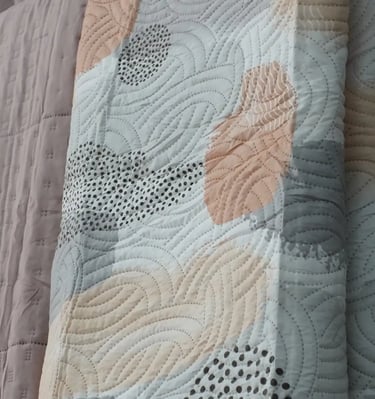 Muestras de colchas en frente de unas cortinas para enseñar los productos que se ofrecen.