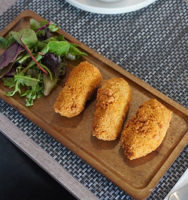 Close-up of crispy chicken croquettes served with mixed green salat.