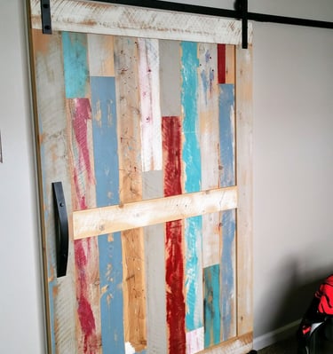 reclaimed wood antique looking custom closet barn door painted in reds, blues, and whites. Colorado Springs remodel.
