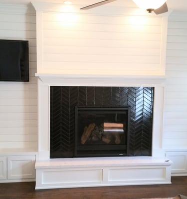 fireplace surround in black tile in a herring bone pattern.  White wood work and mantle. Colorado Springs custom fireplaces.