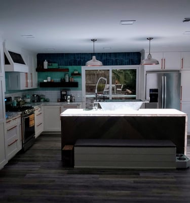 Colorado Springs. Remodeled kitchen with waterfall edge island lit up from underlaid LED lights. 