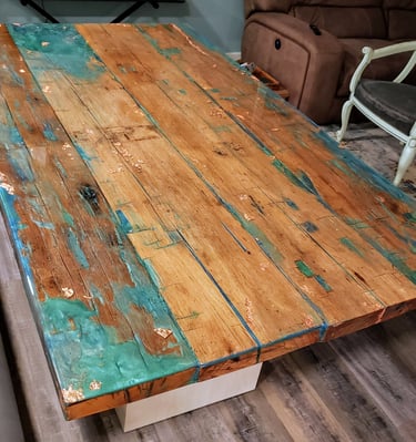 Custom handmade epoxy resin and reclaimed wood dining table.  natural wood colors with spots of blue green epoxy and gold. 