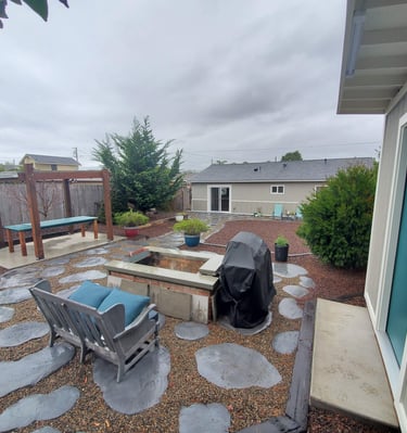Custom backyard shed with teal door, custom decorative concrete stepping stones, and reclaimed wood outdoor table.