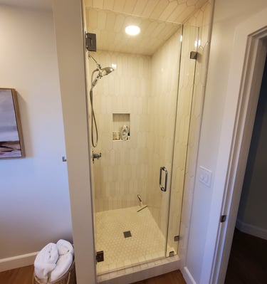 Remodeled shower with white shade tiles on walls and ceiling.  glass door and cut in shelf for shampoo. Colorado Springs.