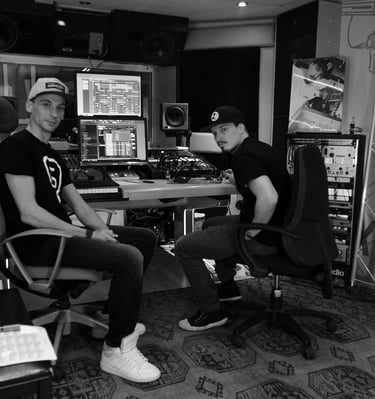 two men sitting in a recording studio producing hip-hop