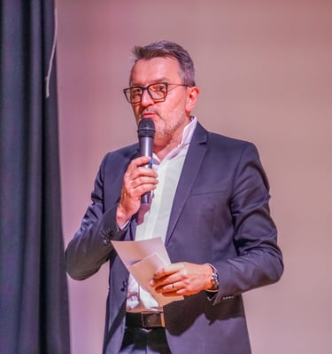 Un animateur de conférence avec un micro et des fiches dans les mains qui parle
