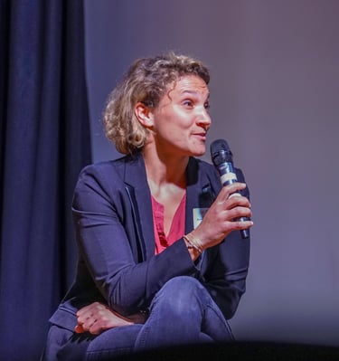 Femme avec un micro assise qui parle pendant une conférence