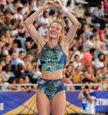 Margot Chevrier fait un cœur avec ses mais sur le tapis de saut après avoir sauté