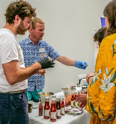 Groupe de personnes autour d'un stand qui dégustent des sauces pimentées