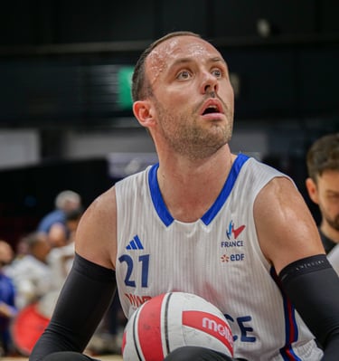 Joueur de rugby fauteuil de l'équipe de France avec le ballon qui regarde au loin
