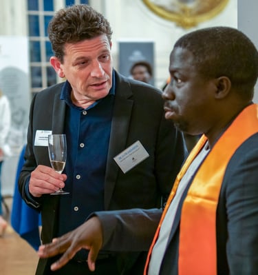 Un homme avec une coupe de champagne qui en regarde un autre et qui discutent