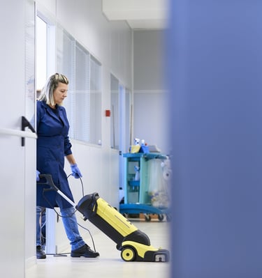 woman vacuuming a carpet with a vacuum cleaner in an office