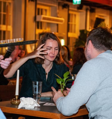 a man and woman sitting at a table with a waiter