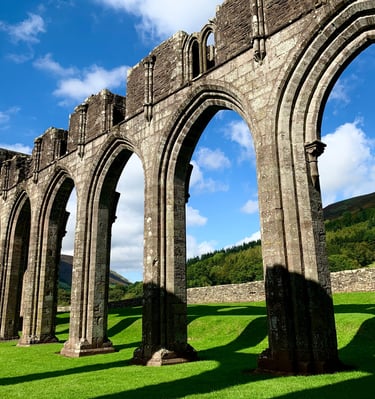 Llanthony priory in the sunshine with the Black Mountains behind it.