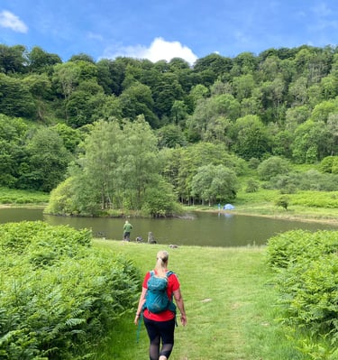 A walker approaches the lush greenness around the Devil's Punchbowl, a lake in the Brecon Beacons, South Wales.