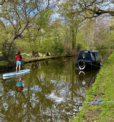 A paddle boarder drifts serenely on the Monmouthshire and Brecon canal using a SUP hired from Bridge 76 Adventures.