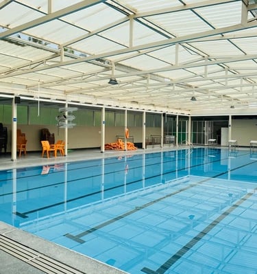 “Clean and spacious indoor swimming pool with seating and equipment around.” Group swimming lesson