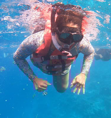 “Person wearing a snorkel mask and life jacket swimming underwater in a clear pool.”