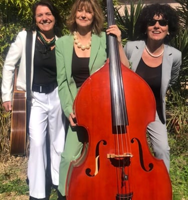 trois femmes en costume qui tiennent une guitare et une contrebasse