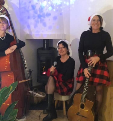 trois femmes en robe rouge et noire à carreaux autour d'une cheminée,une guitare et une contrebasse