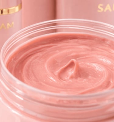 Formula coral de SAM Cosméticos con textura cremosa en envase abierto.