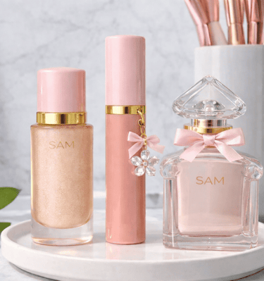 Set elegante de maquillaje SAM Cosméticos con iluminador y labial en tonos rosa y dorado.