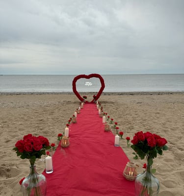 demande en mariage sur la plage avec une arche en forme de coeur orné de fleurs et d'un tapis rouge