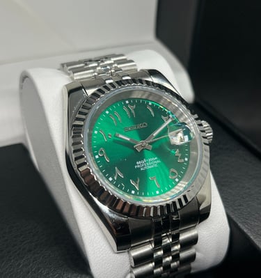 Seiko automatic watch with green Arabic dial and stainless steel jubilee bracelet in a display box.
