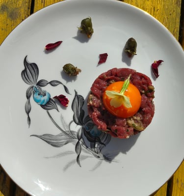 Venison tartar with an egg yolk, primrose garnish, dandelion capers and rose petals