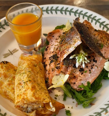 Rolled egg, salmon with crispy skin, wild garlic flower garnish, sea buckthorn juice