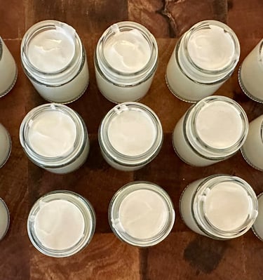 glass jars full of essential oil hand cream in the process of being made
