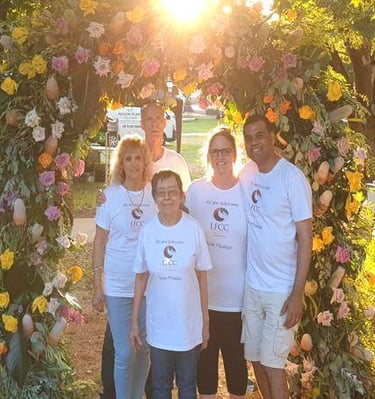 a group of people standing in front of a flower arch