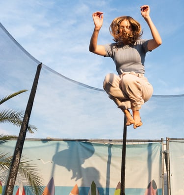 Photo of a girl jumping on a trampoline in sunset light