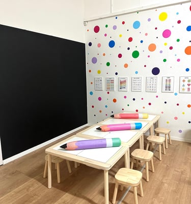 Lernbereich mit großen Stiften und Kindertischen – Vorbereitung auf den Schulstart in der Spielgrupp