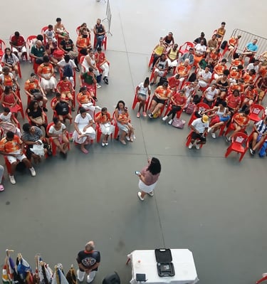 uma mulher ao centro e varias pessoas sentadas em cadeiras