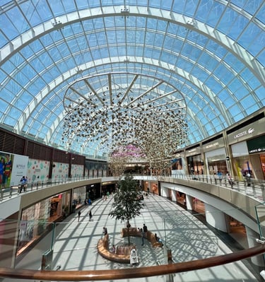 a large atrium with a tree in the middle inside Dubai Hills Mall