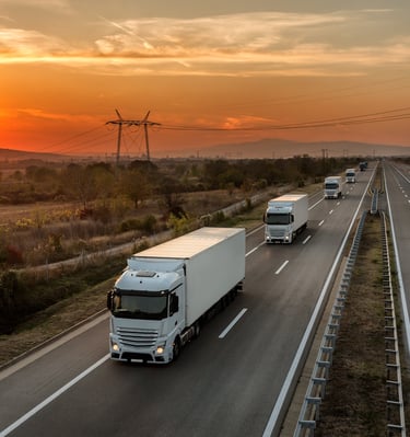a truck driving down a highway with a sunset