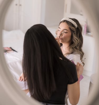 Bridal makeup artist applying soft glam foundation in natural light on wedding day