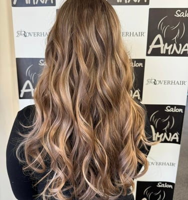 Back view of long wavy hair with honey blonde balayage highlights and professional styling.