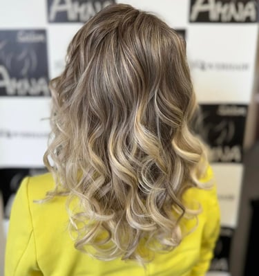 Back view of wavy ash blonde balayage hair with highlights and soft curls.