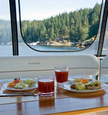 Gourmet eggs benedict breakfast served on a yacht with scenic forest and lake views.