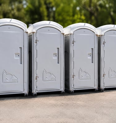Fila de baños portátiles blancos numerados, listos para instalación en Venezuela