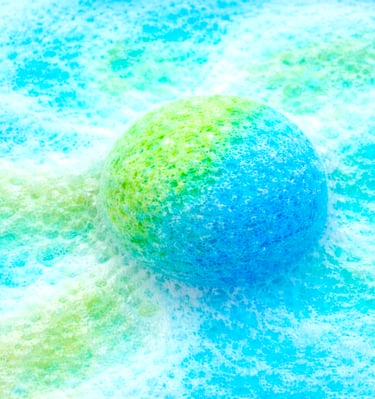 Extra large blue and green bath bomb fizzing with rich, colorful foam.