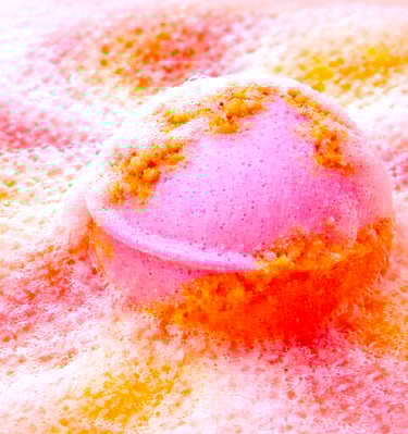 XL pink and coral bath bomb dissolving with dense foam and vibrant color bloom.