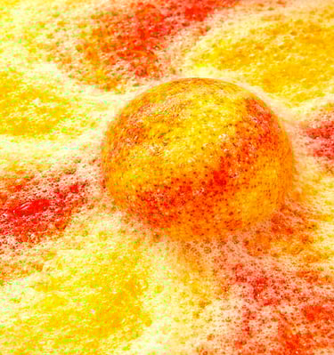 XL bath bomb producing golden yellow and orange foam with heavy fizz.