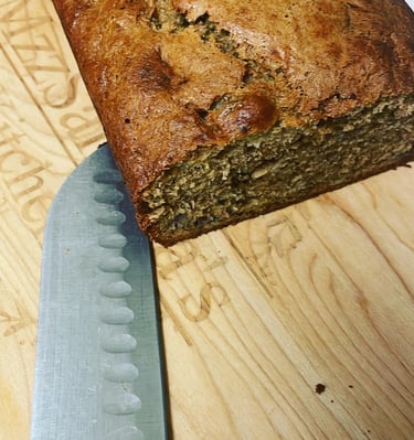 Freshly baked homemade banana bread loaf on a wooden cutting board with a slicing knife.