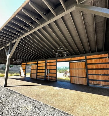 Rustic timber frame pavilion with open wood sliding doors and elegant chandelier lighting.
