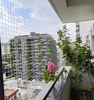 Installation team fitting a pigeon net on a balcony with cityscape in the background.