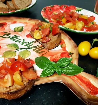 Homemade tomato bruschetta served on a decorative wooden board with fresh basil and yellow cherry tomatoes.