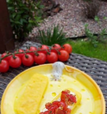 Grilled polenta slices topped with fresh tomato bruschetta on a yellow plate with cherry tomatoes.